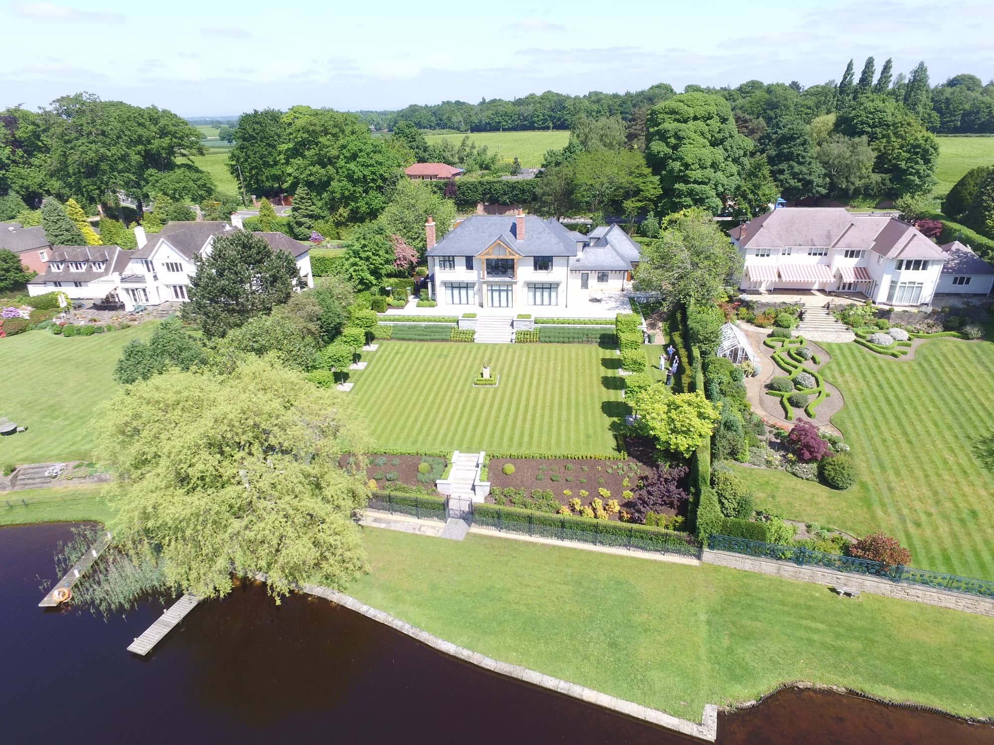 an aerial view of a large house with a lake in front of it.
